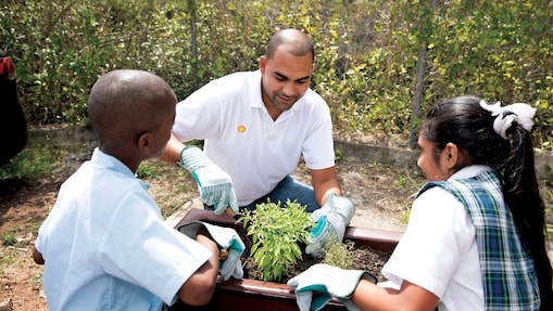 Man and students planting a tree