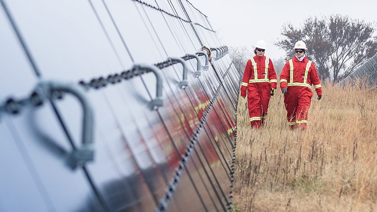 Two Shell employees walking between massive solar panels