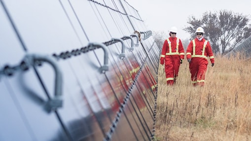 Two Shell employees walking between massive solar panels