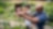 Man helping a smiling child water plants in a garden