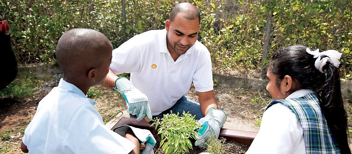Man and students planting a tree